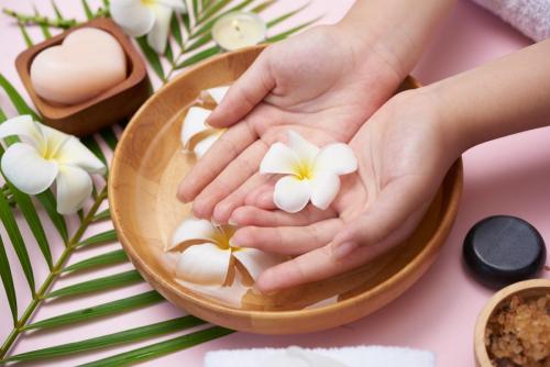 Woman soaking her hands in bowl of water and flowers, Spa treatm